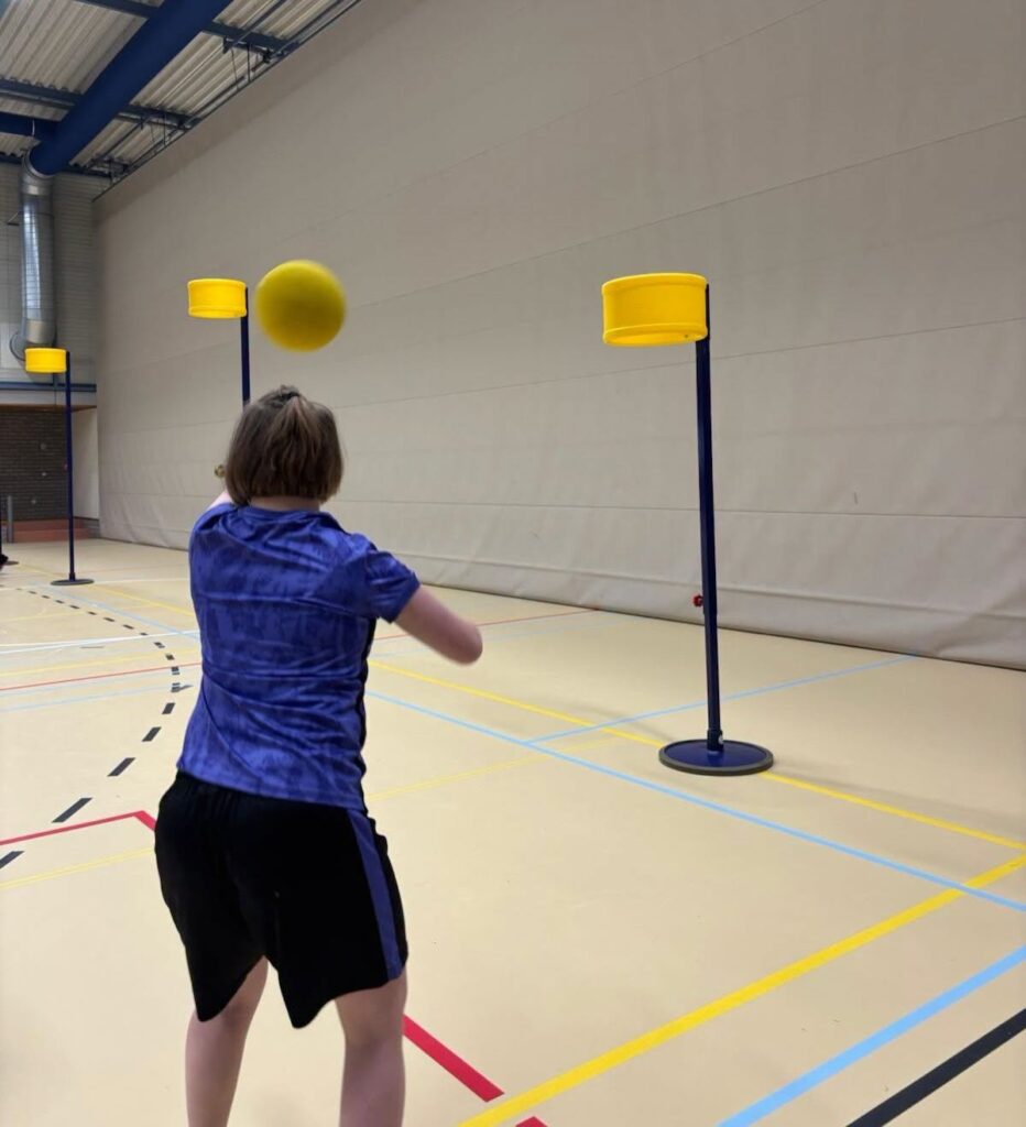 Een deelnemer oefent met gooien naar de korf.