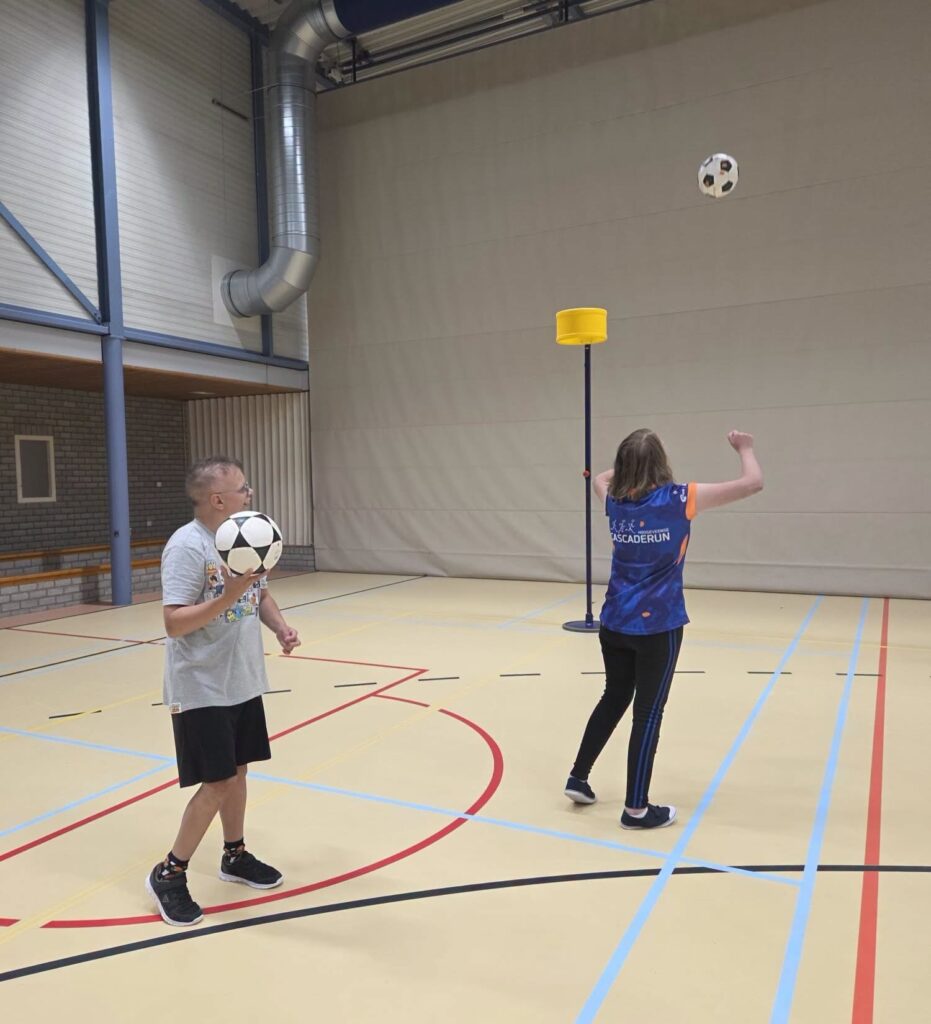 Deelnemers oefenen met het gooien naar de korf tijdens Passend Korfbal.
